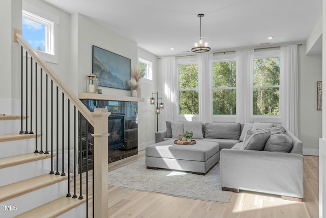 living room featuring a tile fireplace, stairway, baseboards, and wood finished floors