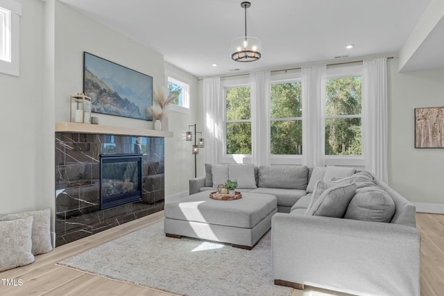 living area with recessed lighting, baseboards, wood finished floors, and a high end fireplace