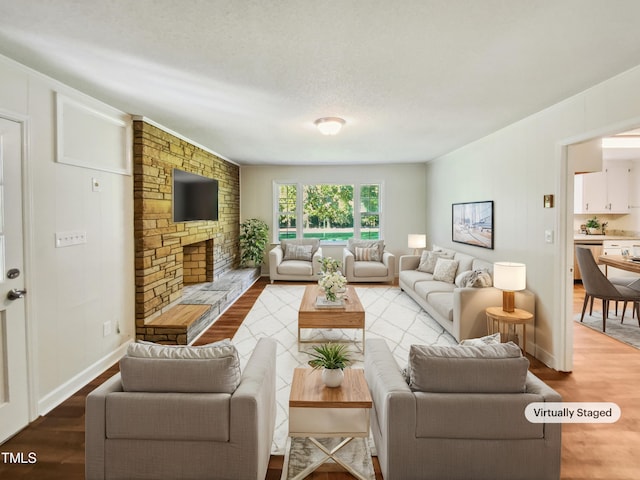 living room with hardwood / wood-style floors, a textured ceiling, and a stone fireplace