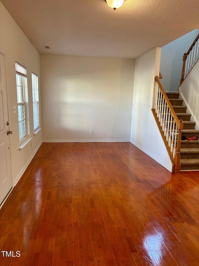 unfurnished living room featuring dark wood-type flooring and a textured ceiling