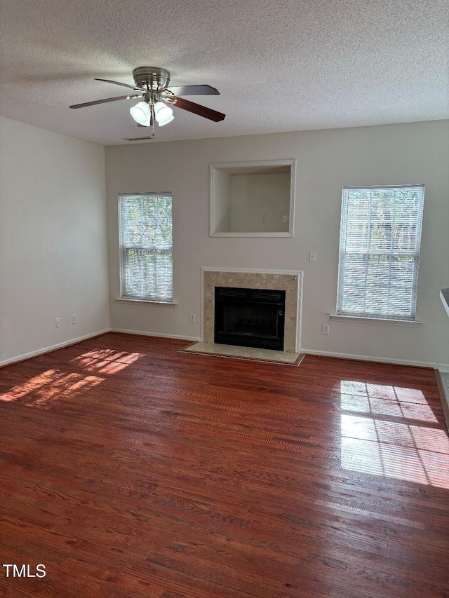 unfurnished living room with ceiling fan, a textured ceiling, and dark hardwood / wood-style floors