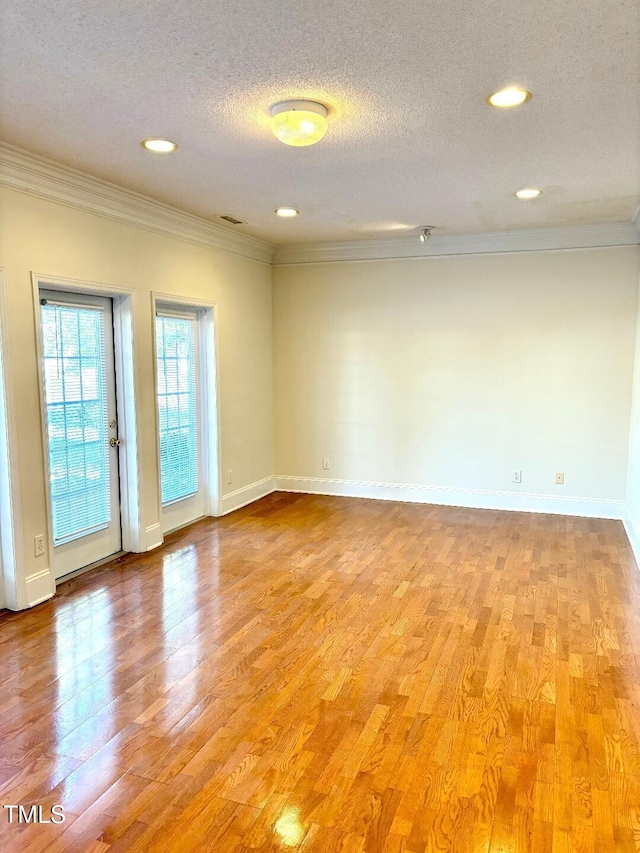 empty room featuring a textured ceiling, ornamental molding, and light hardwood / wood-style flooring