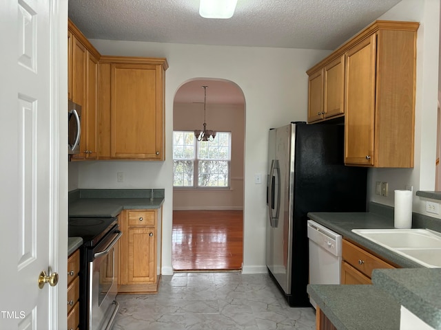 kitchen featuring light hardwood / wood-style flooring, a textured ceiling, an inviting chandelier, and stainless steel appliances