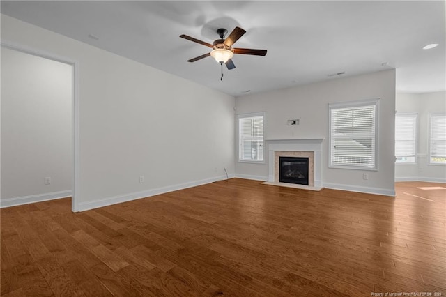 unfurnished living room featuring ceiling fan, a tiled fireplace, and hardwood / wood-style floors