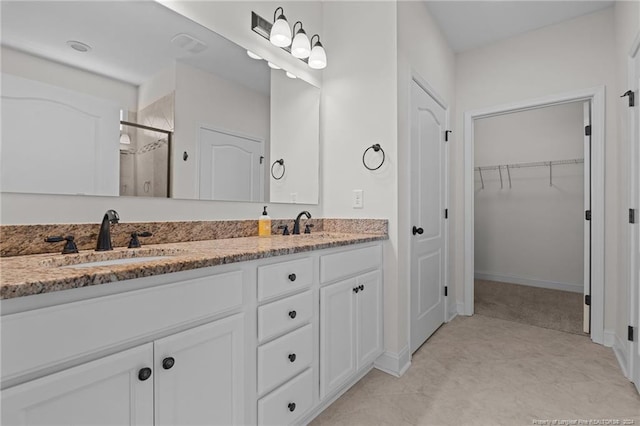 bathroom featuring a shower with door and vanity