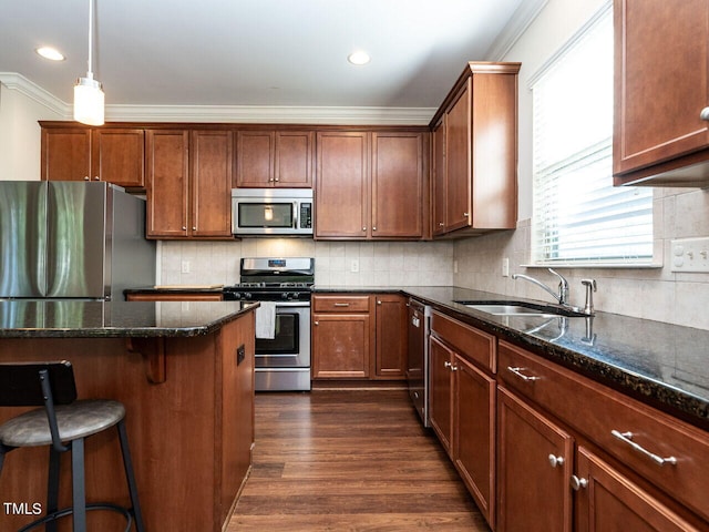 kitchen featuring appliances with stainless steel finishes, pendant lighting, dark stone countertops, and sink