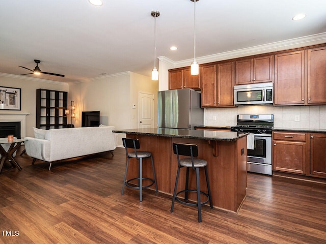 kitchen with dark stone counters, a kitchen island, dark wood-type flooring, hanging light fixtures, and appliances with stainless steel finishes