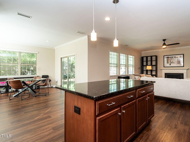 kitchen featuring pendant lighting, crown molding, a kitchen island, dark stone countertops, and dark hardwood / wood-style floors