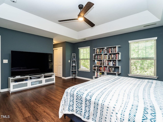 bedroom with multiple windows, ceiling fan, a closet, and dark hardwood / wood-style floors