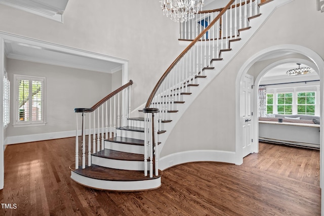 stairway with a baseboard radiator, wood-type flooring, and ornamental molding