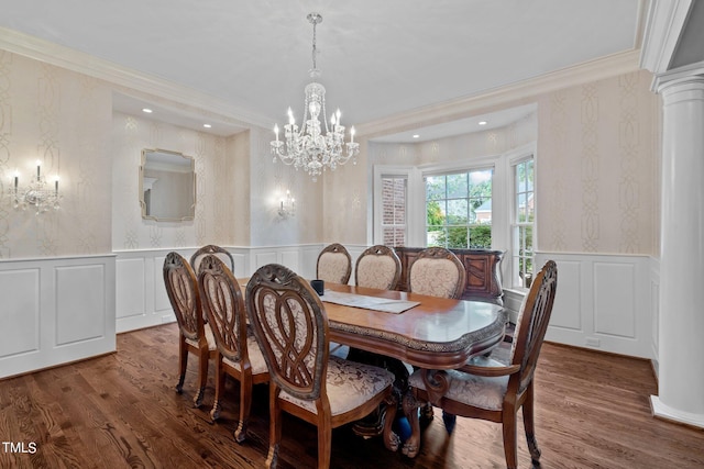 dining space featuring dark wood-type flooring, decorative columns, ornamental molding, and an inviting chandelier