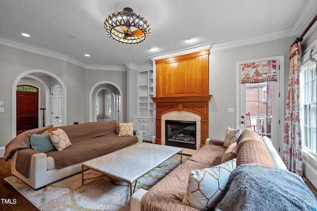 living room with light hardwood / wood-style floors, built in features, ornamental molding, and a large fireplace