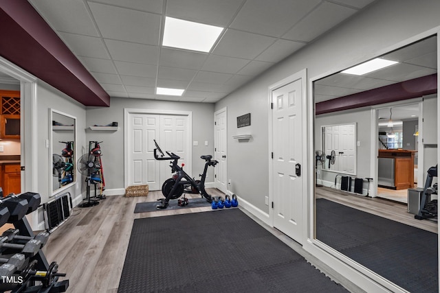 workout room with wood-type flooring and a paneled ceiling