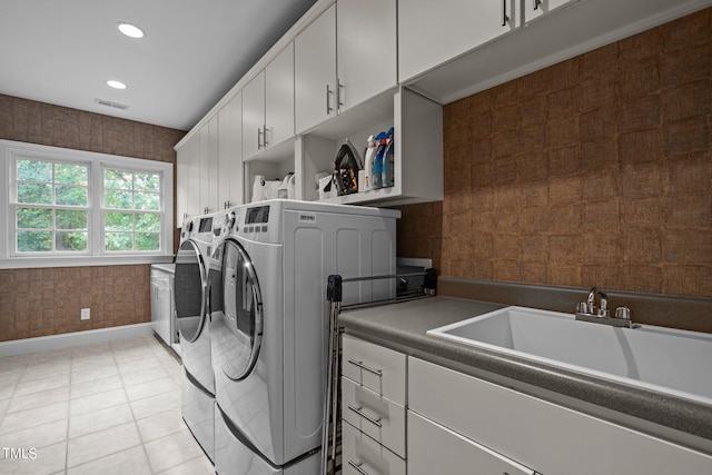 laundry room featuring sink, light tile patterned floors, cabinets, and separate washer and dryer