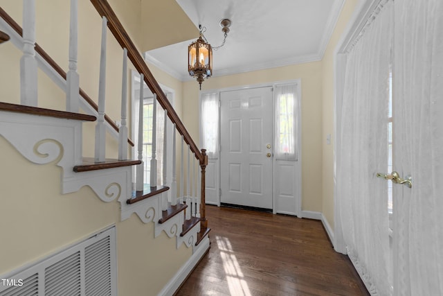 entryway featuring ornamental molding, a chandelier, dark hardwood / wood-style flooring, and a healthy amount of sunlight