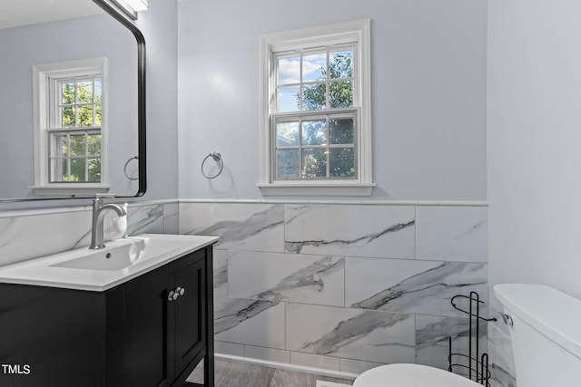 bathroom featuring vanity, tile walls, toilet, and a wealth of natural light