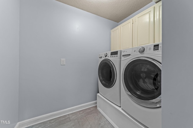 washroom featuring light tile patterned floors, cabinets, a textured ceiling, and washer and clothes dryer