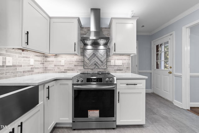 kitchen featuring wall chimney exhaust hood, ornamental molding, white cabinets, and stainless steel electric range