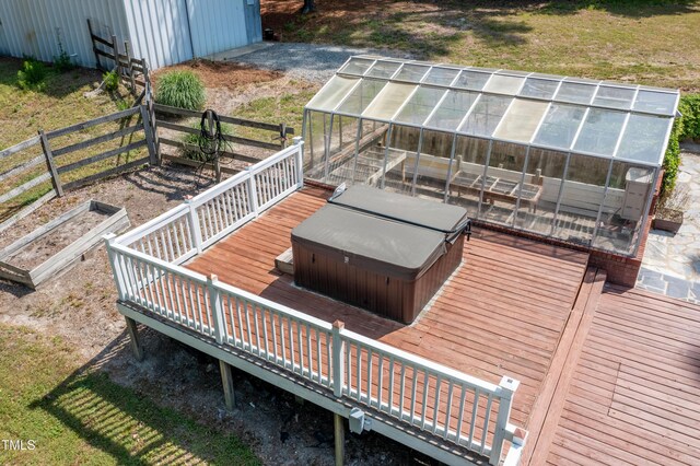 wooden deck with a covered hot tub, an outdoor structure, and a greenhouse