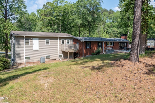 rear view of house with central AC unit, a chimney, a yard, and a deck