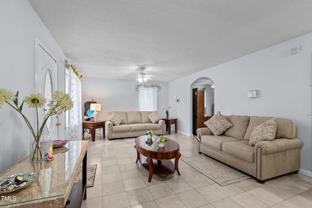 tiled living room with a textured ceiling and ceiling fan