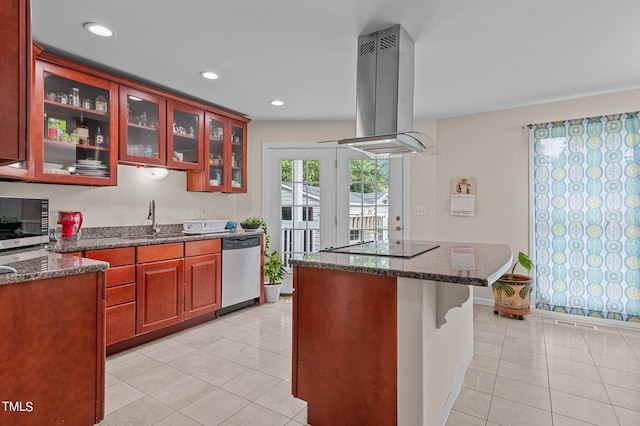 kitchen with stainless steel appliances, dark stone countertops, sink, light tile patterned flooring, and island exhaust hood