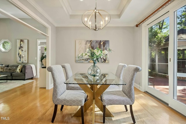 dining room with light hardwood / wood-style floors, crown molding, an inviting chandelier, and a tray ceiling