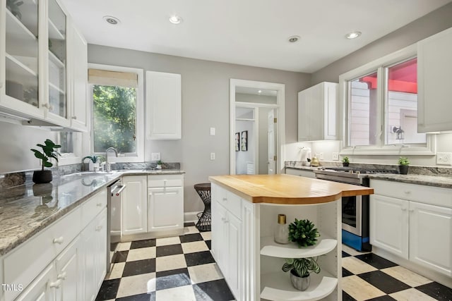 kitchen featuring white cabinets, appliances with stainless steel finishes, sink, wooden counters, and a center island