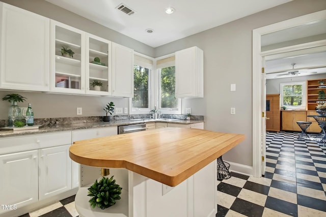 kitchen with dishwasher, wood counters, white cabinetry, ceiling fan, and a breakfast bar area