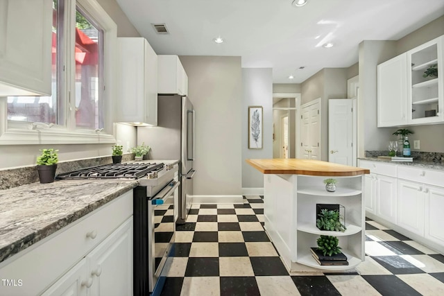 kitchen featuring white cabinetry, light stone counters, and high end stove