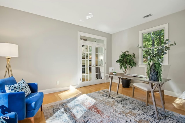 home office featuring wood finished floors, visible vents, baseboards, and french doors