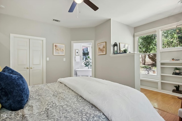 bedroom with wood finished floors, visible vents, and a ceiling fan