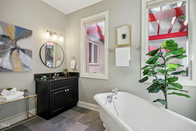 full bath featuring a soaking tub, baseboards, and vanity