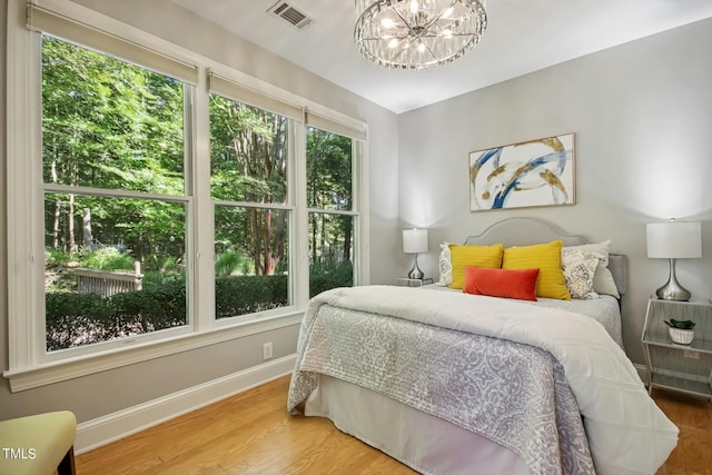 bedroom featuring baseboards, wood finished floors, a chandelier, and visible vents