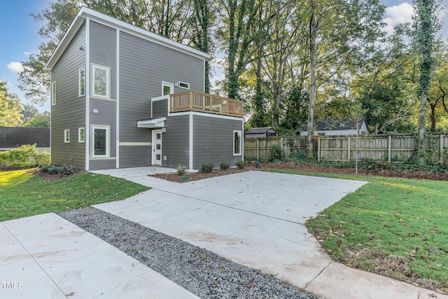 rear view of house featuring a patio area, a lawn, a balcony, and fence