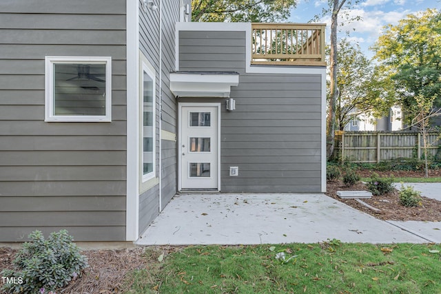 entrance to property featuring fence, a patio, and a balcony