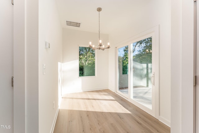 unfurnished dining area featuring light hardwood / wood-style floors and an inviting chandelier