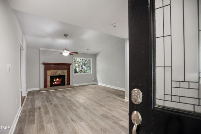 unfurnished living room with ceiling fan, light wood-type flooring, and a tiled fireplace