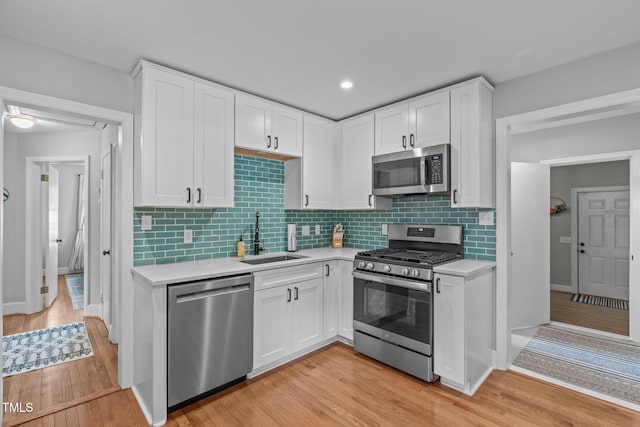 1209 Edgevale Rd, Durham, NC 27701 - kitchen with stainless steel appliances, light countertops, white cabinets, light wood-style flooring, and backsplash