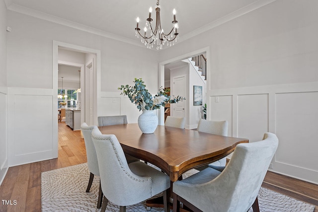 dining area with ornamental molding, a notable chandelier, and hardwood / wood-style floors