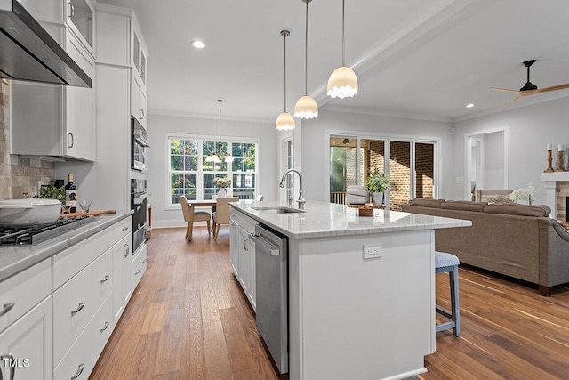 kitchen with sink, a kitchen island with sink, white cabinetry, and extractor fan