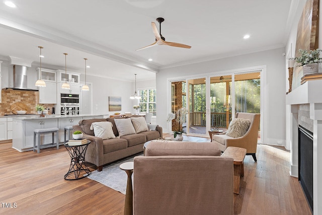 living room featuring light hardwood / wood-style flooring, ceiling fan, and crown molding