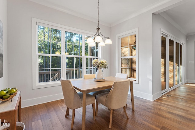 dining area featuring ornamental molding, a notable chandelier, and dark hardwood / wood-style flooring