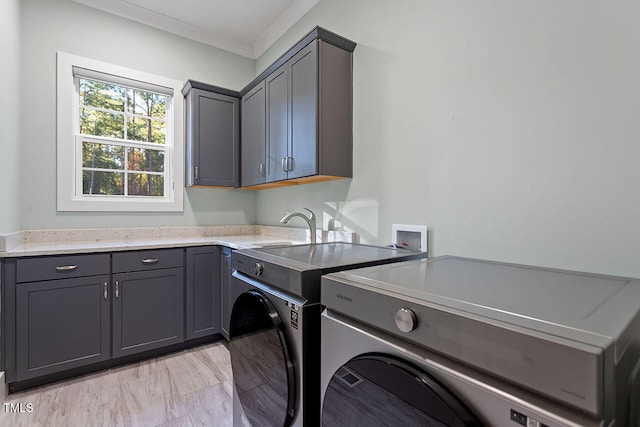 washroom with sink, crown molding, washer and dryer, and cabinets