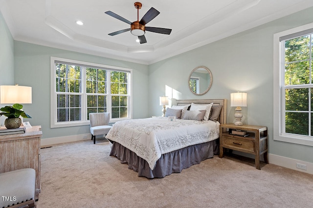 bedroom with ornamental molding, light colored carpet, a tray ceiling, and ceiling fan