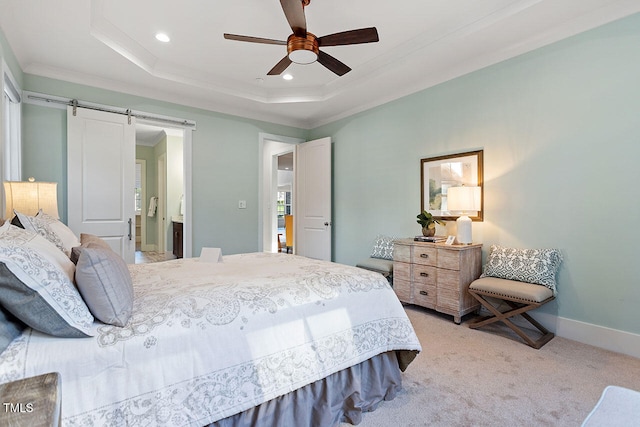 carpeted bedroom with ceiling fan, a tray ceiling, ensuite bathroom, and a barn door