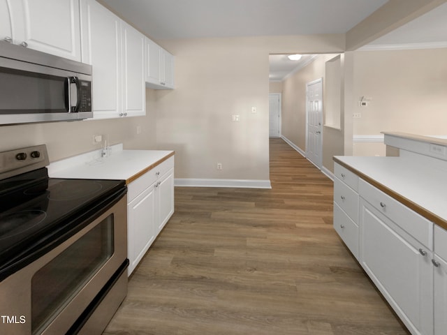 kitchen featuring ornamental molding, appliances with stainless steel finishes, light hardwood / wood-style floors, and white cabinetry