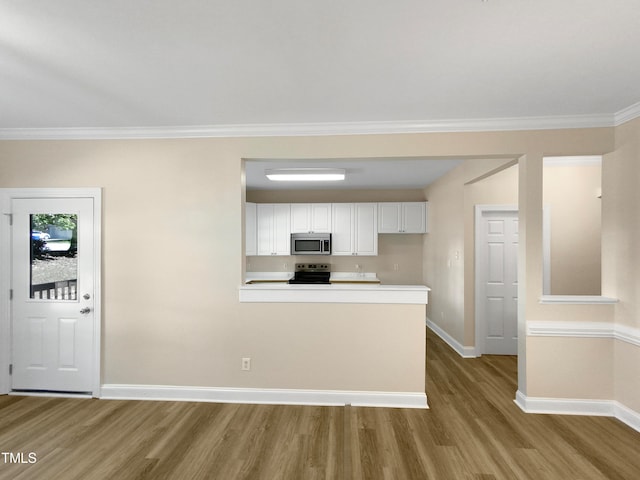 kitchen featuring appliances with stainless steel finishes, light wood-type flooring, ornamental molding, and white cabinetry