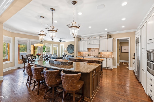 kitchen featuring hanging light fixtures, a breakfast bar area, dark hardwood / wood-style flooring, and a spacious island