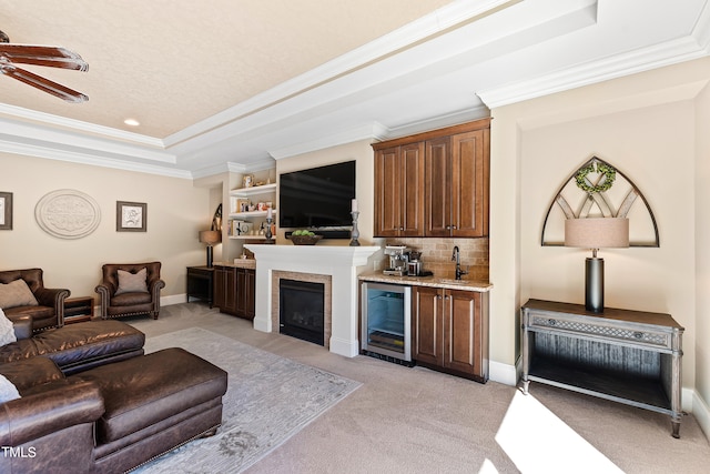 bar with tasteful backsplash, beverage cooler, a tray ceiling, light carpet, and ornamental molding